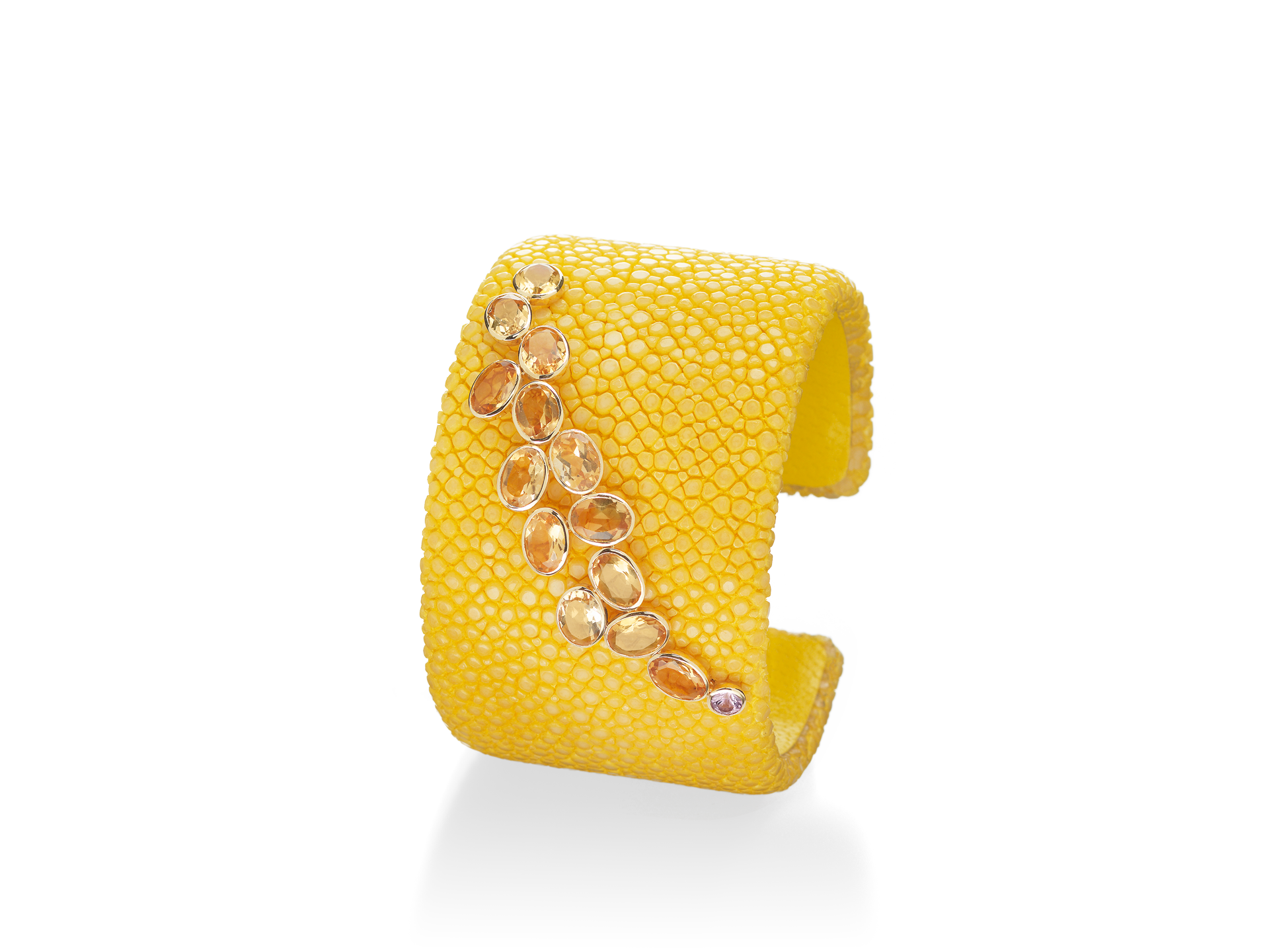 Der Armreif GALUCHAT ARMREIF CITRIN von Schullin ist ein breiter, strukturierter Armreif aus 18 Karat Gelbgold mit einem diagonalen Cluster aus Citrin und orangefarbenen Edelsteinen auf weißem Hintergrund.