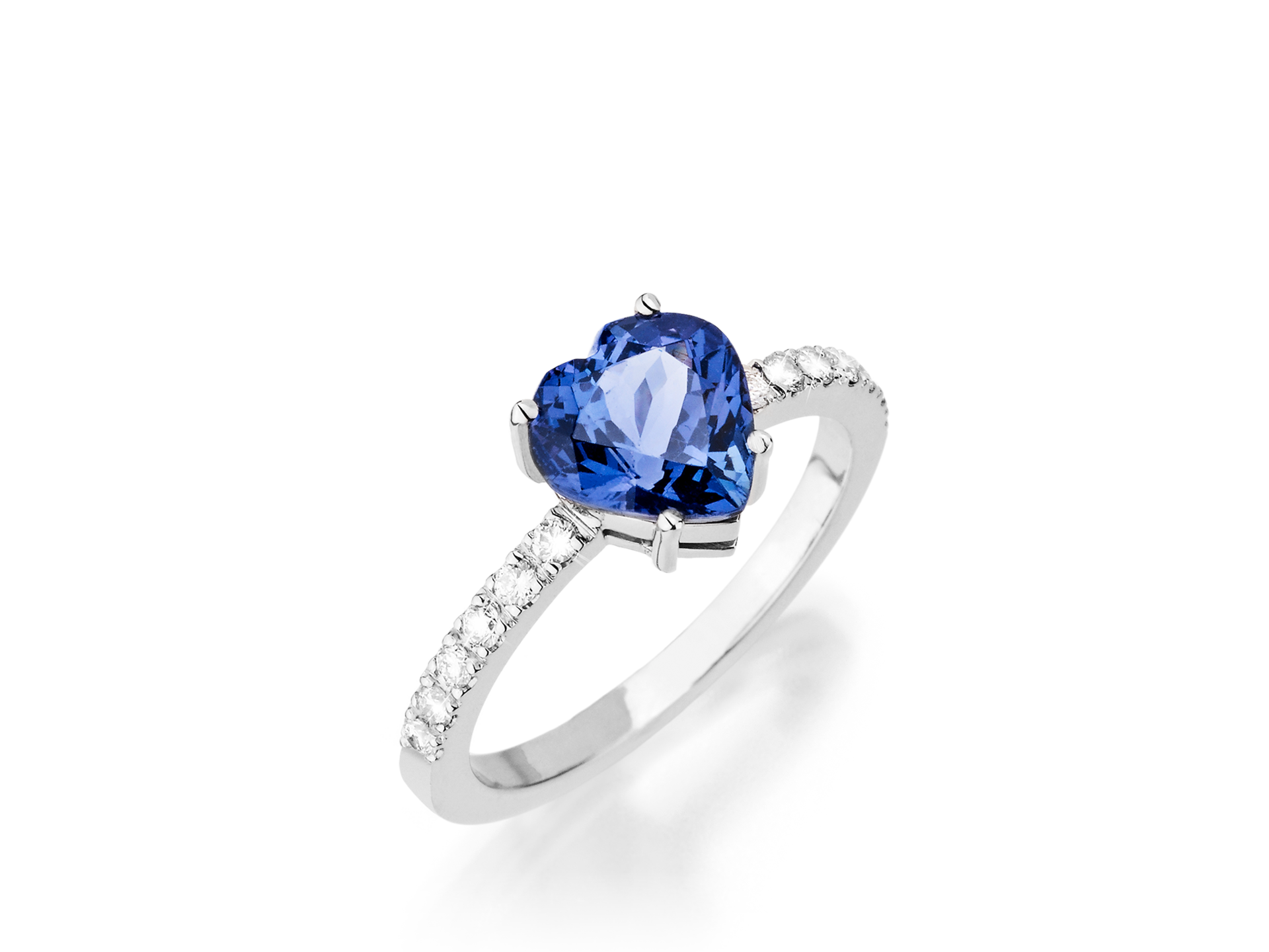 Der Schullin TANSANIT RING HEART ist ein Silberring mit einem herzförmigen blauen Tansanit in der Mitte und kleinen runden weißen Diamanten auf dem Band, die vor einem schlichten weißen Hintergrund stehen.