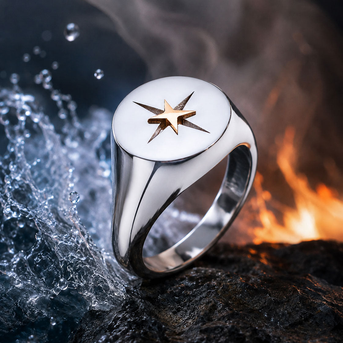 Der ELEMENTS RING SILBER von Schullin zeigt ein auffälliges goldenes Sterndesign auf Silber, das auf einem nassen Felsen zwischen spritzendem Wasser und Flammen für einen dramatischen Kontrast der Elemente präsentiert wird.