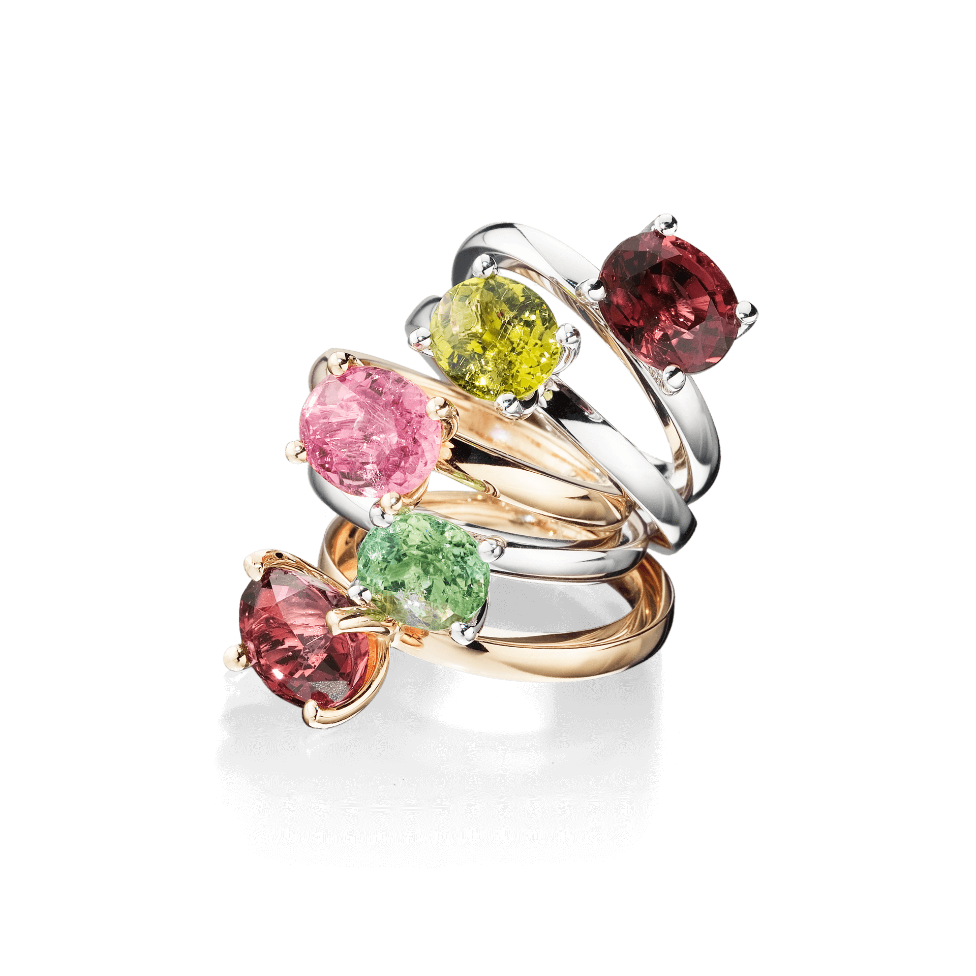 Eine kunstvoll arrangierte Kollektion von 18 Karat Roségold-, Gold- und Silberringen mit leuchtenden Edelsteinen in rosa, grünen, gelben und roten Farbtönen wird vor schwarzem Hintergrund präsentiert. Das Highlight dieses Ensembles ist der TURMALIN RING FANCY T von Schullin, geschmückt mit einem champagnerfarbenen Turmalin.