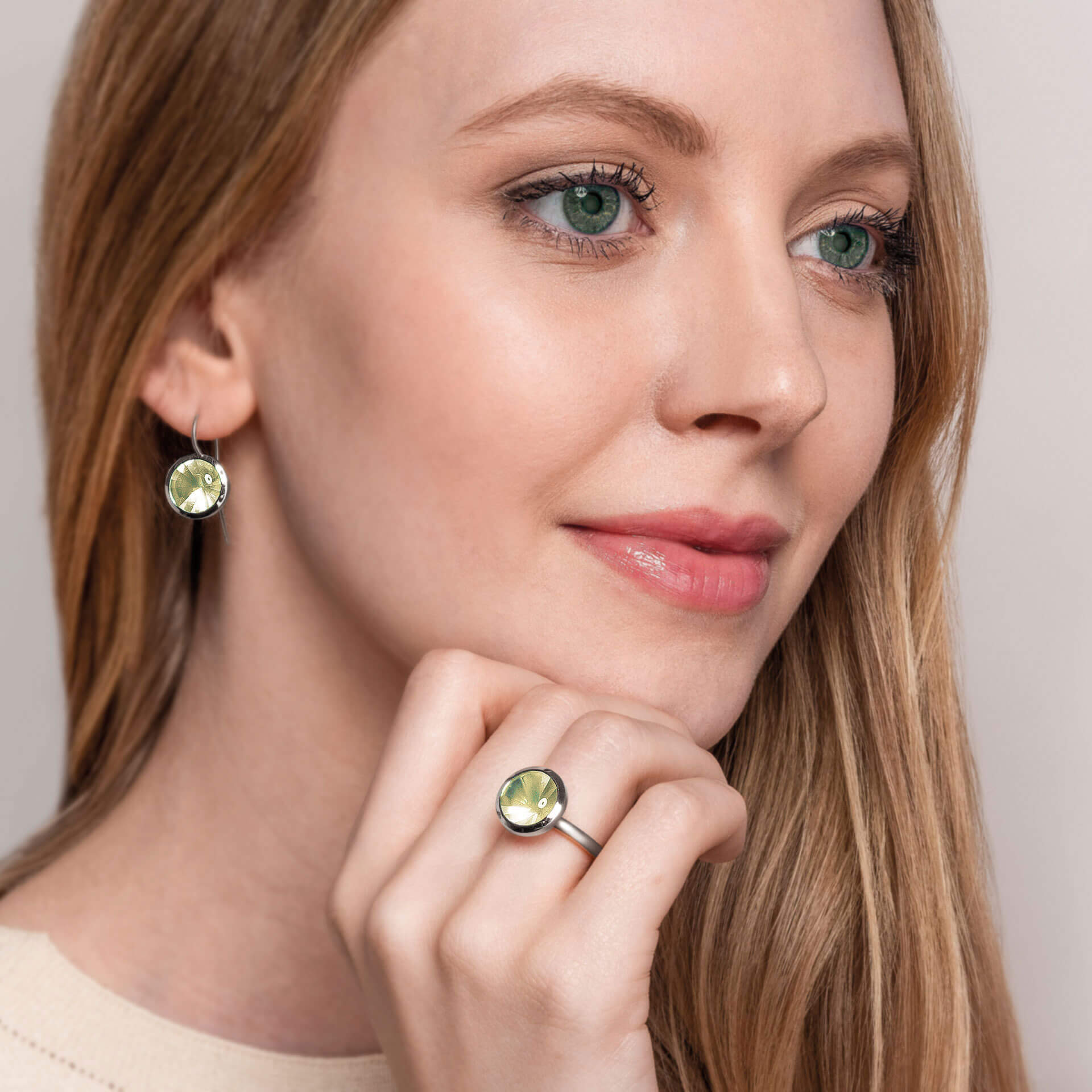 Eine Frau mit langen blonden Haaren trägt passenden Schullin-Schmuck mit Zitronenquarz-Steinen. Ihre LEMONQUARZ OHRRINGE BUFFTOP-Ohrringe und ihr Ring ergänzen sich perfekt, während sie vor einem neutralen Hintergrund nachdenklich zur Seite blickt.