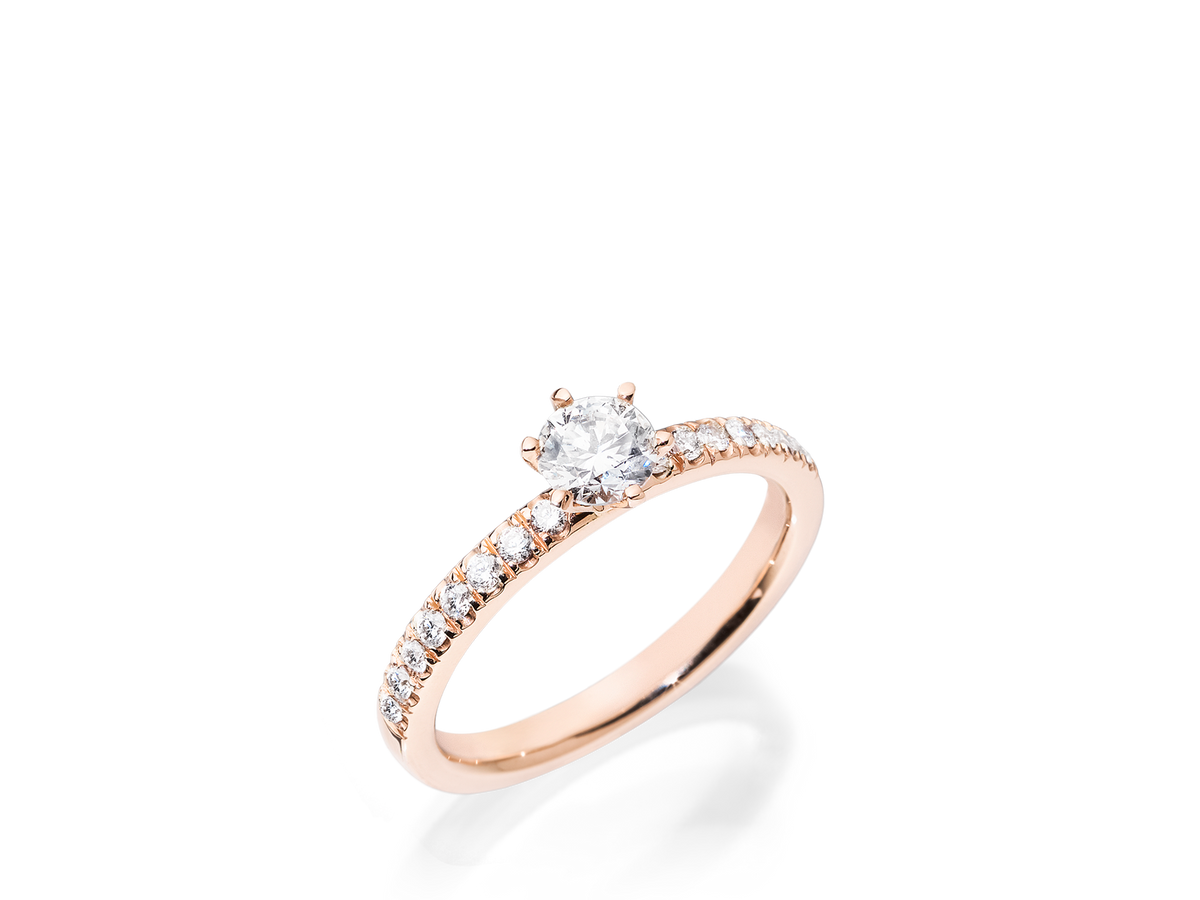 Der Schullin RING GRACE 0,25 CARAT ist ein Verlobungsring aus Roségold mit einem runden Solitär-Diamanten in der Mitte und kleineren Diamanten entlang des Rings, der auf weißem Hintergrund dargestellt ist.