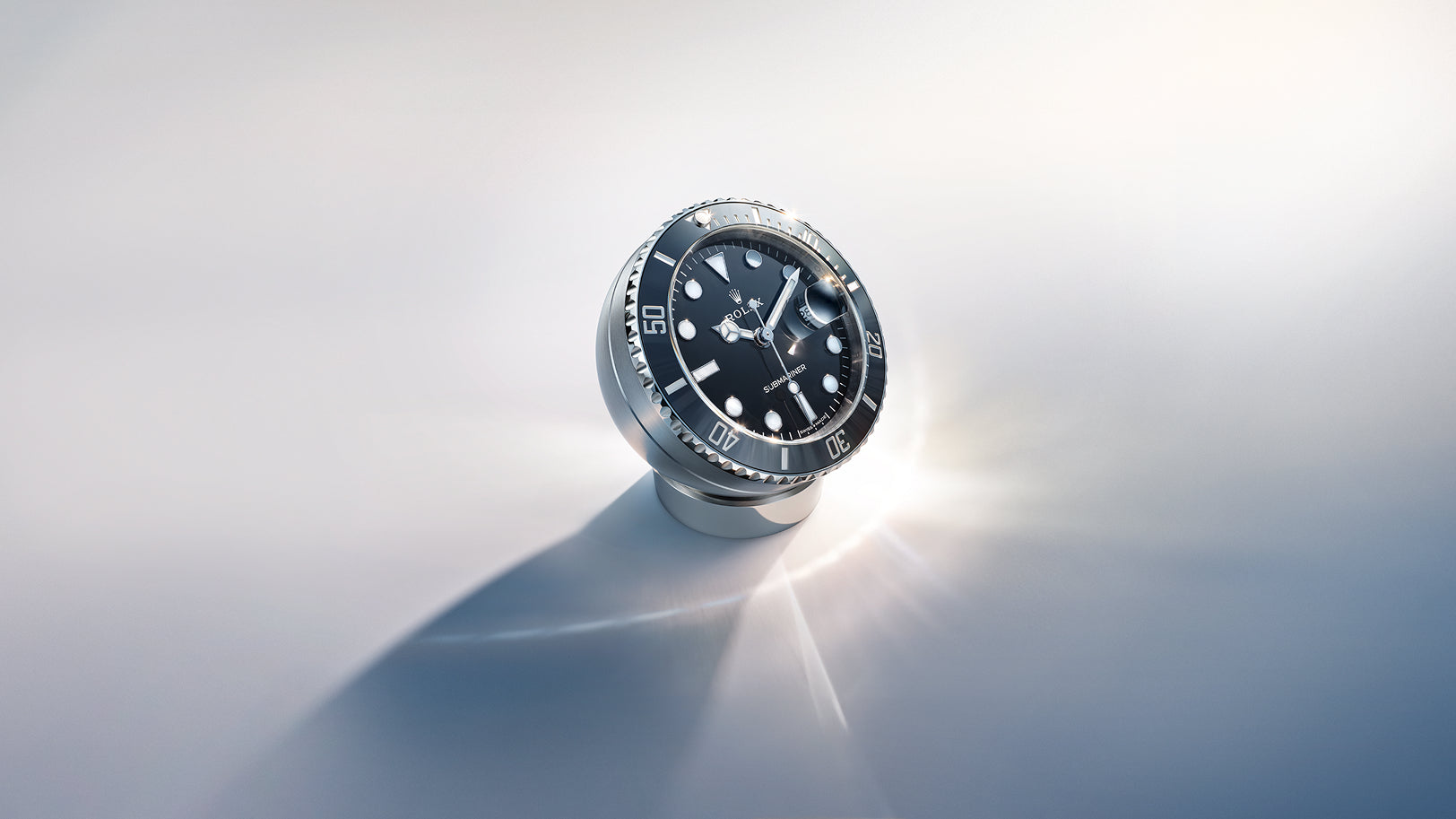 Eine luxuriöse Armbanduhr mit schwarzem Zifferblatt und silberner Lünette steht aufrecht auf einer weißen Fläche und wirft einen weichen Schatten und eine strahlende Lichtreflexion. Die Uhr verfügt über große Indizes und Zeiger, die Uhrzeit ist auf ca. 10:11 Uhr eingestellt.