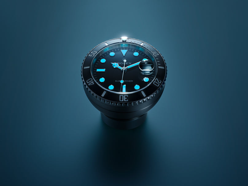 Eine Nahaufnahme einer Rolex Submariner mit leuchtend blauen Stundenmarkierungen und Zeigern vor einem dunkelblauen Hintergrund, die die detaillierte Lünette und die glänzende Oberfläche der Uhr hervorheben.