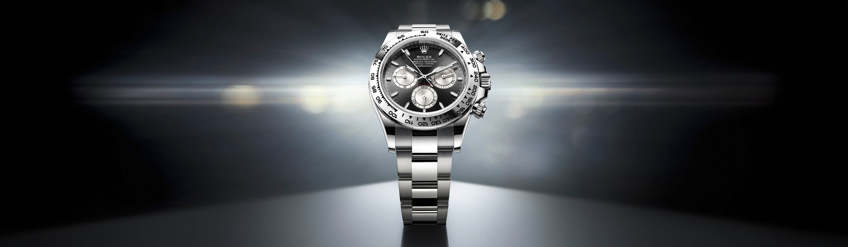 Eine Luxusuhr aus Edelstahl mit schwarzem Zifferblatt und drei Hilfszifferblättern wird vor einem dunklen, strahlenden Hintergrund präsentiert. Das Licht hebt die polierten Oberflächen und komplizierten Details der Uhr hervor und sorgt so für ein anspruchsvolles und elegantes Erscheinungsbild.