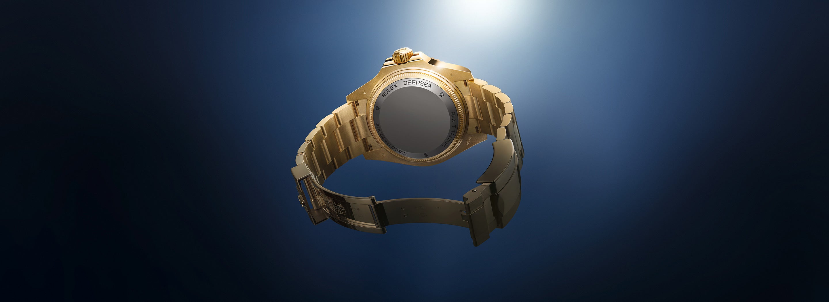 Eine goldene Armbanduhr mit Gliederarmband wird vor einem dunkelblauen Hintergrund mit Farbverlauf präsentiert und von oben von einem Scheinwerfer beleuchtet, wodurch ihr elegantes und luxuriöses Design hervorgehoben wird. Der Fokus liegt auf der Uhrschließe und der Rückseite.