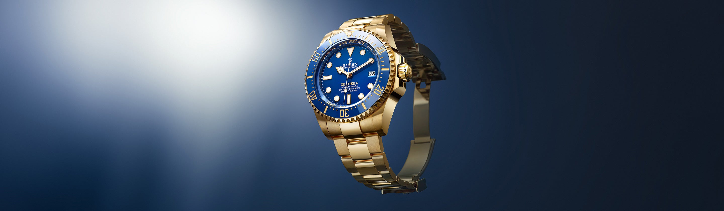 Eine goldene Armbanduhr mit blauem Zifferblatt und Metallarmband leuchtet vor einem dunklen Hintergrund und betont ihre komplizierten Details und ihr elegantes Design.