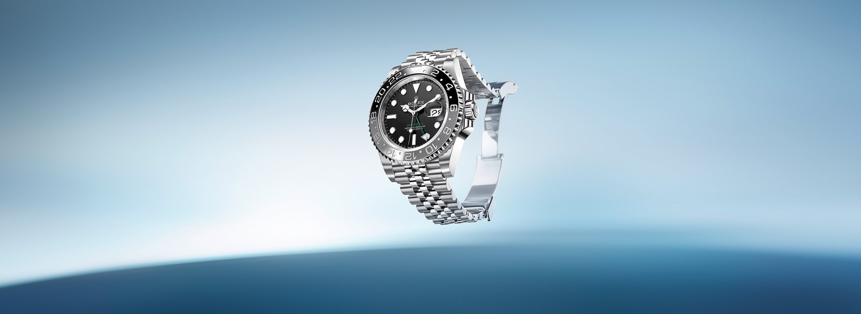 Eine silberne Armbanduhr mit schwarzem Zifferblatt und detaillierter Lünette ist vor einem Hintergrund mit Farbverlauf in Blau zu sehen. Die Uhr verfügt über ein Metallarmband und Leuchtmarkierungen, die ihr ein luxuriöses Aussehen verleihen.