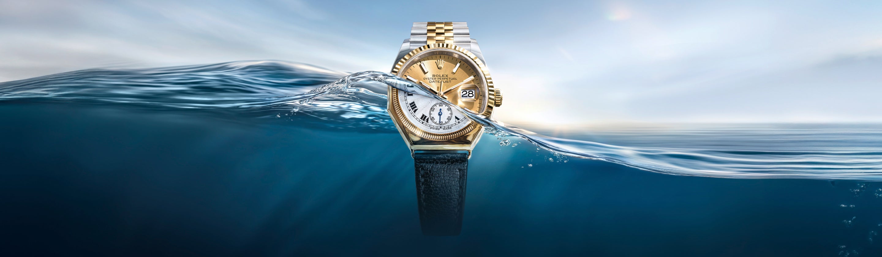 Eine goldene Armbanduhr, die teilweise in klares, blaues Wasser getaucht ist, mit der oberen Hälfte über der Oberfläche und der unteren Hälfte darunter, vor einem hellen, verschwommenen Himmelshintergrund.