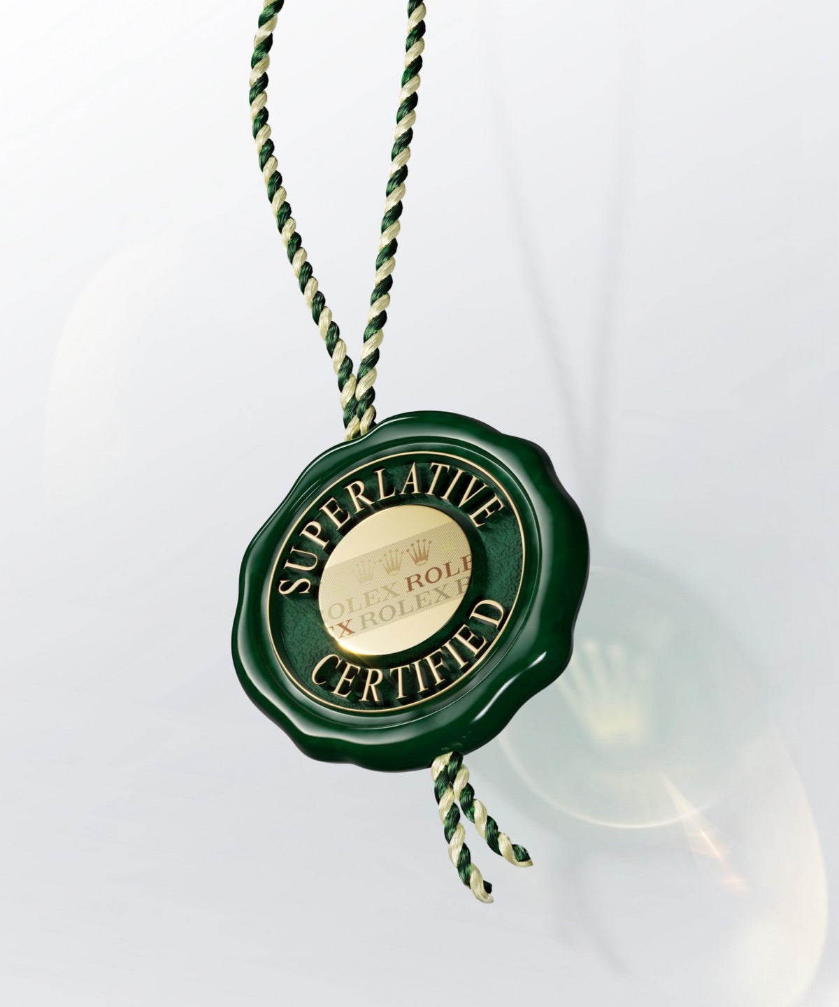 Ein grünes Siegel mit der Aufschrift „Superlative Certified“ in goldener Schrift, dem geprägten Text „Rolex“ und einem Kronenlogo hängt an einer gedrehten grün-goldenen Kordel vor hellem Hintergrund.