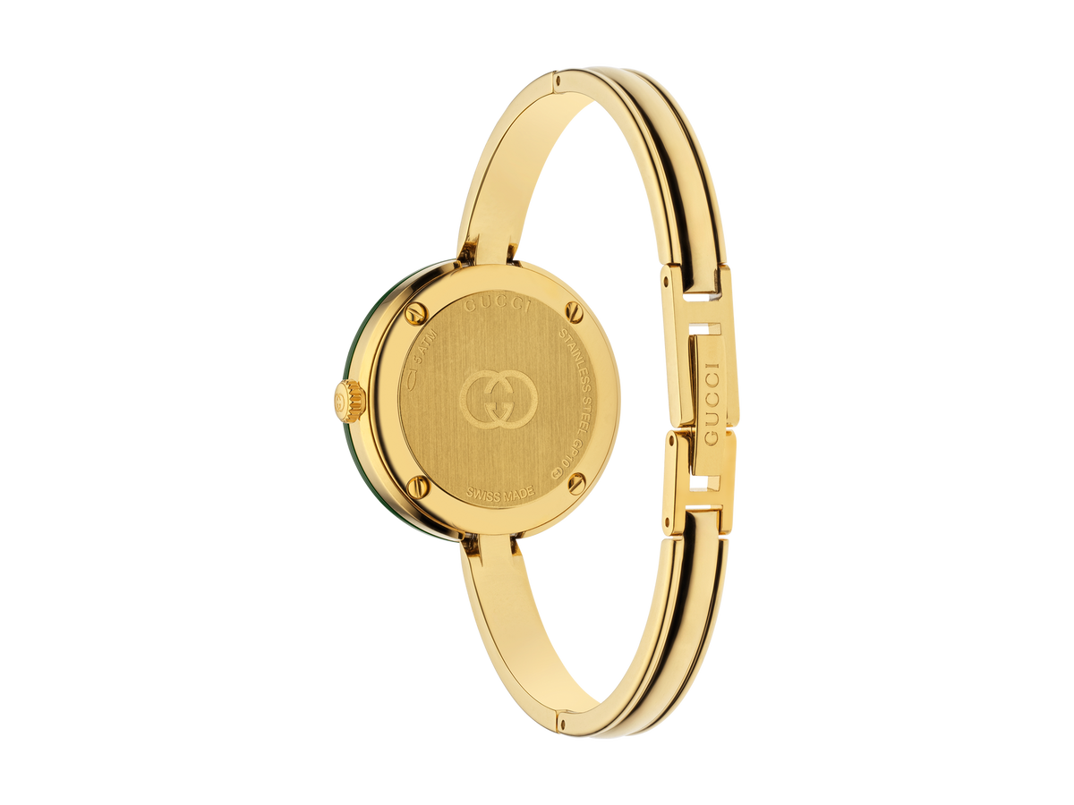 Eine goldene Schullin GUCCI PLAY Armbanduhr, von hinten gesehen, mit dem eingravierten Markenzeichen auf dem runden Gehäuse und der Schließe des Armbands, unterstrichen durch ein schlichtes, minimalistisches Design.