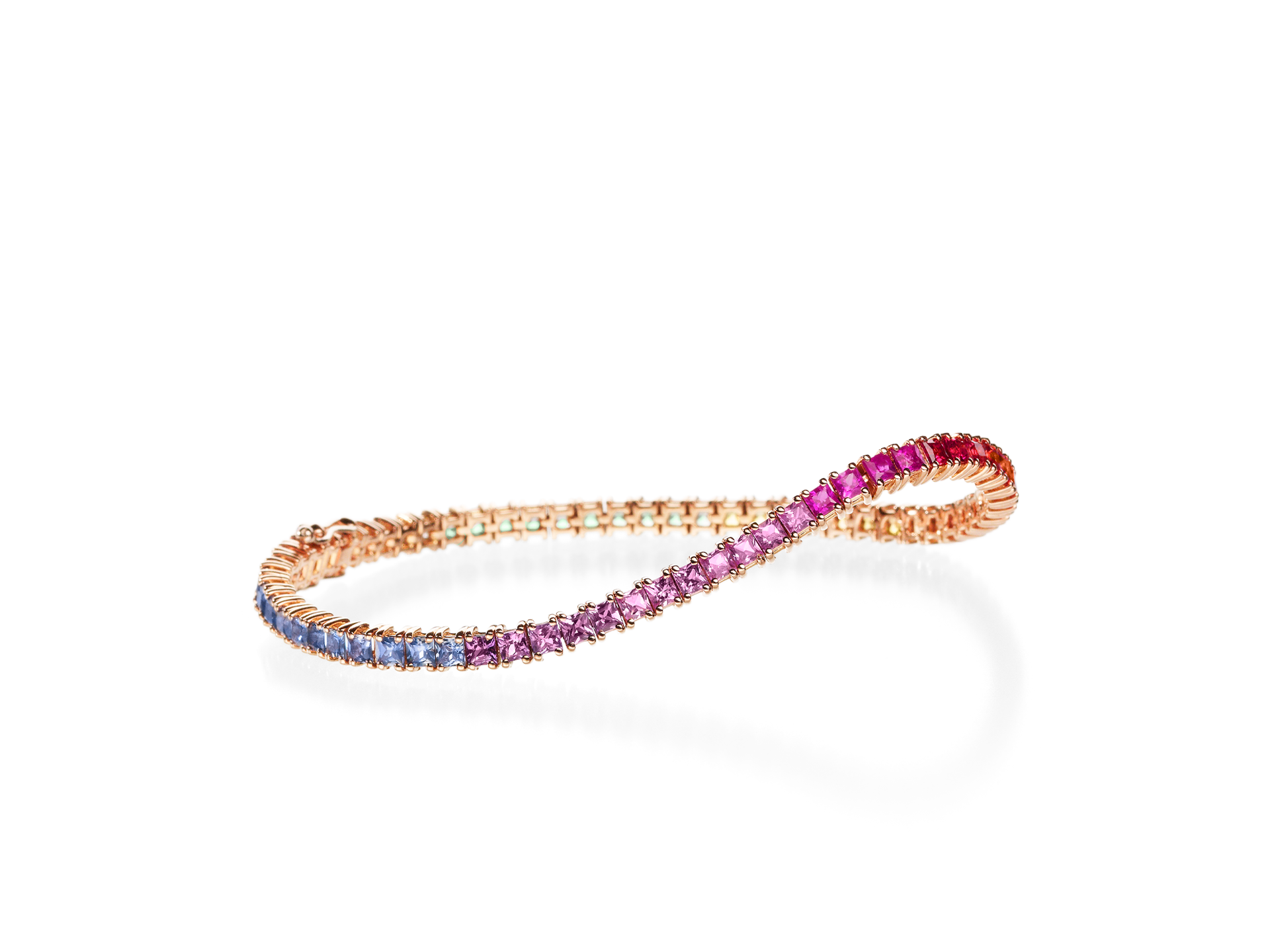 Das SAPHIR ARMBAND RAINBOW von Schullin zeigt eine zarte goldene Unendlichkeitsschleife, die mit Edelsteinen verziert ist, die von Blau über Violett zu Rosa changieren und auf einem weißen Hintergrund zu sehen sind.