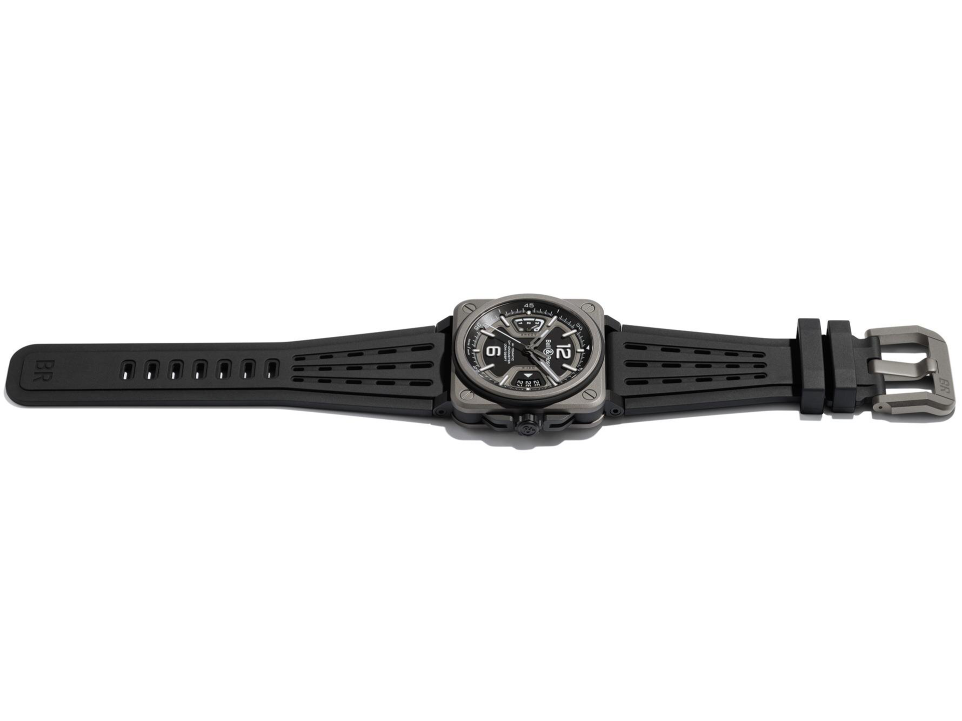 Die Schullin BELL & ROSS BR-X3 BLACK TITANIUM ist eine schwarz-silberne, quadratische Armbanduhr mit schwarzem Kautschukarmband, weißen Ziffern und Zeigern auf schwarzem Zifferblatt, flach mit geöffneter Dornschließe.