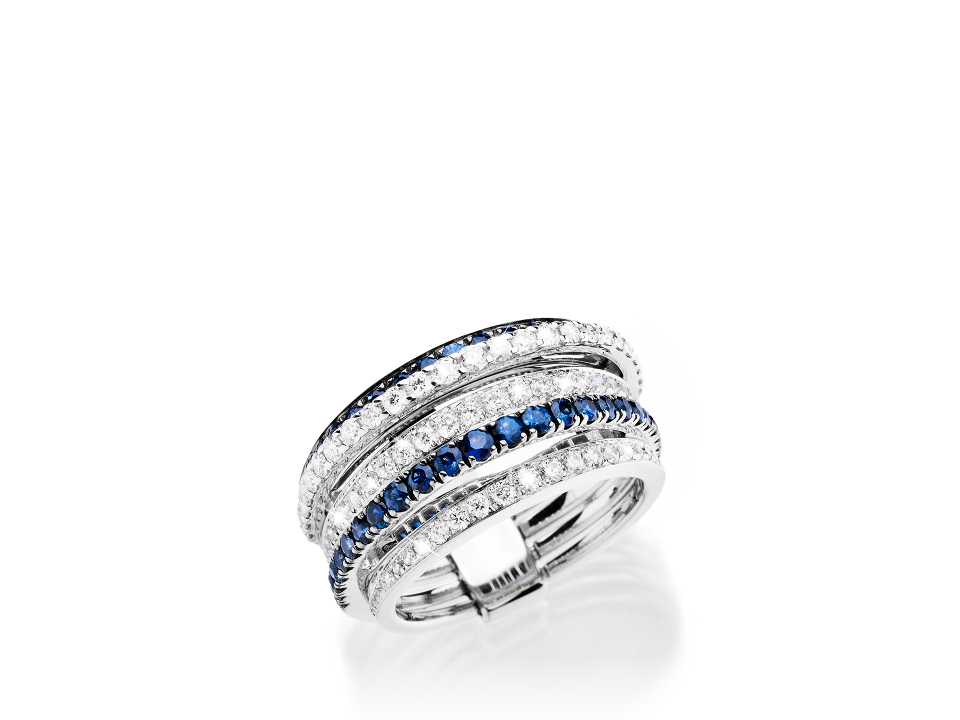 Der SAPHIR RING von Schullin ist eine Silberkreation mit mehreren Bändern, die abwechselnd mit blauen Saphiren und klaren Edelsteinen verziert sind, wodurch ein schimmernder Effekt entsteht. Das Design ist sowohl elegant als auch kompliziert und hebt eine Mischung aus funkelnden Steinen hervor, die in 18 Karat Weißgold auf einem schlichten weißen Hintergrund eingefasst sind.