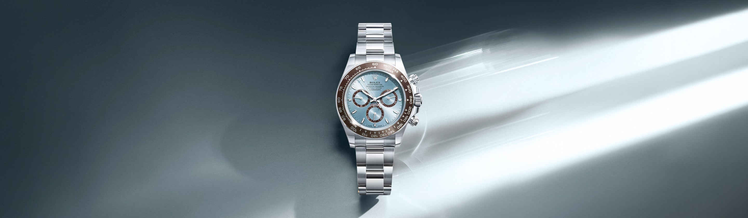 Eine luxuriöse silberne Armbanduhr mit hellblauem Zifferblatt und diamantbesetzter Lünette auf grauem Hintergrund mit einem Lichtstrahl, der über die rechte Seite scheint.