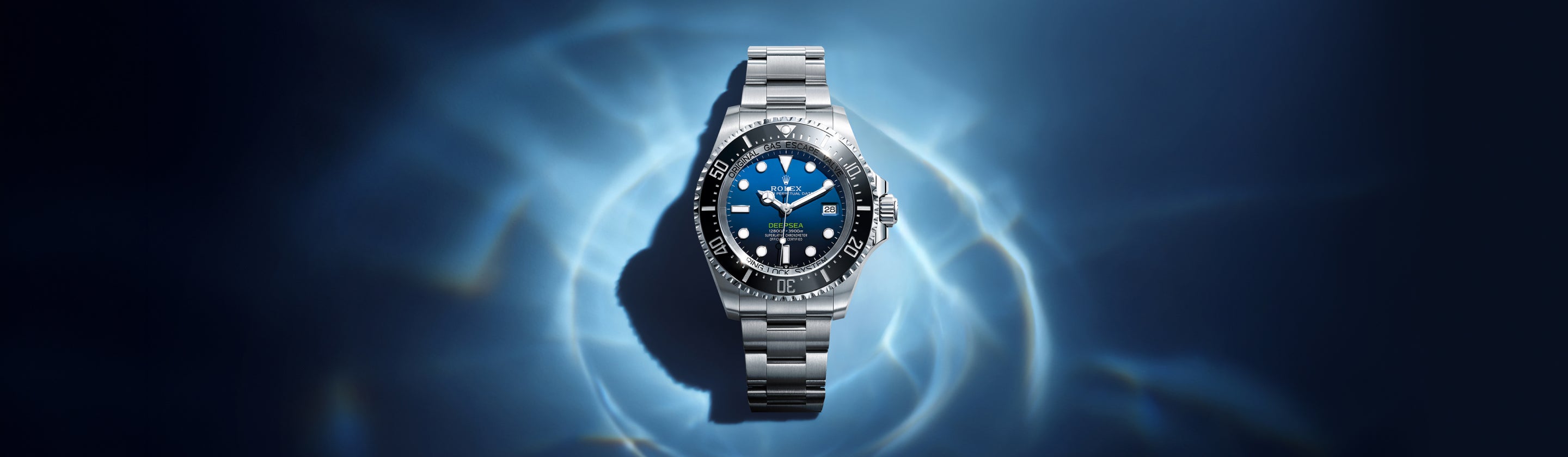 Eine silberne Luxusarmbanduhr mit blauem und schwarzem Zifferblatt wird vor einem dunkelblauen Hintergrund mit hellen Mustern, die an Wasserreflexe erinnern, dargestellt.