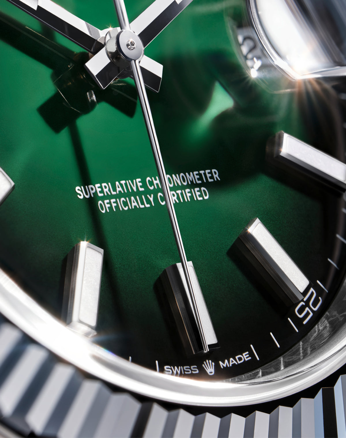 Nahaufnahme eines Luxusuhrenzifferblatts mit grünem Hintergrund, silbernen Zeigern und Stundenmarkierungen. Der Text "Superlative Chronometer Officially Certified and Swiss Made" befindet sich am unteren Rand. Eine geriffelte Lünette ist teilweise sichtbar.