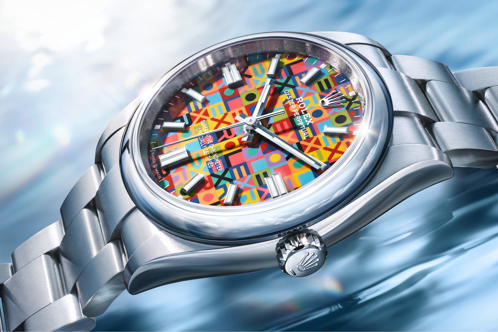 Eine Nahaufnahme einer silbernen Rolex-Uhr mit einem bunten, geometrisch gemusterten Zifferblatt, das auf einer reflektierenden, wasserähnlichen blauen Oberfläche liegt. Das Sonnenlicht erzeugt Glanzlichter und Reflexionen auf der Uhr und dem Hintergrund.