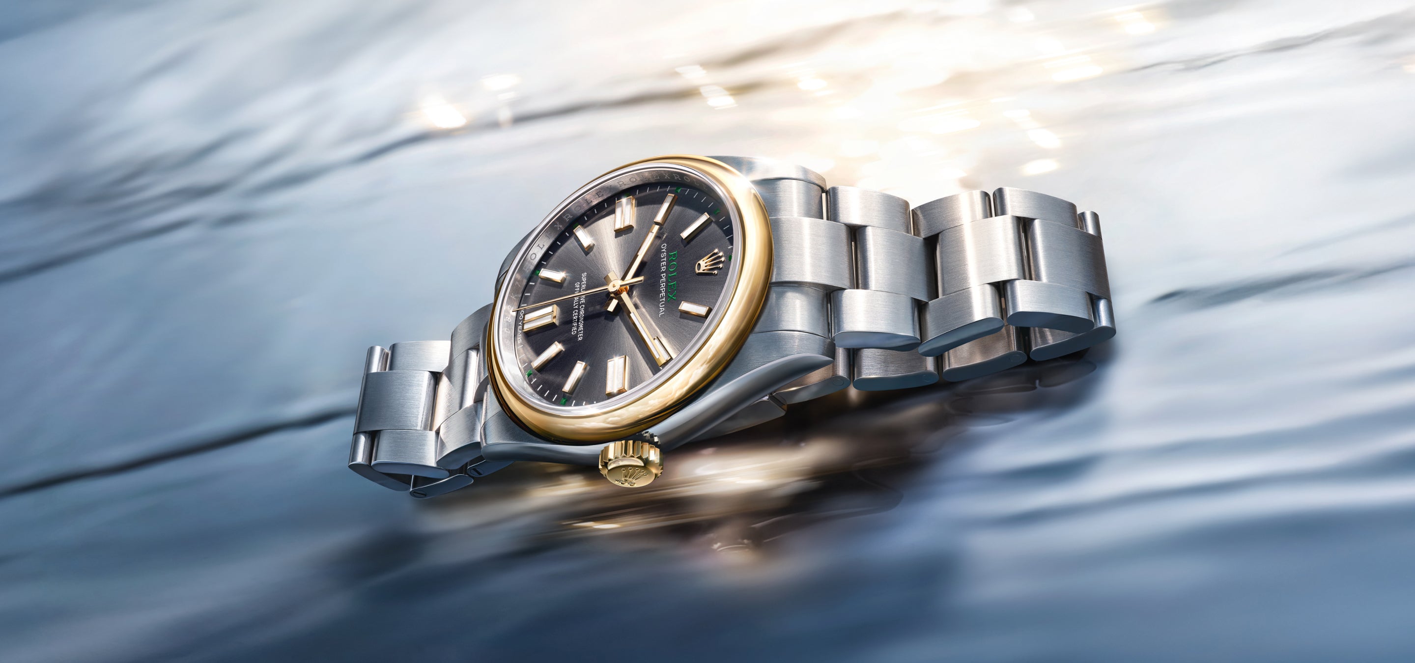 Eine luxuriöse Armbanduhr mit schwarzem Zifferblatt, goldener Lünette und silbernem Metallband liegt auf einer glänzenden, gewellten Metalloberfläche, die das Licht reflektiert und einen raffinierten, eleganten Look erzeugt.