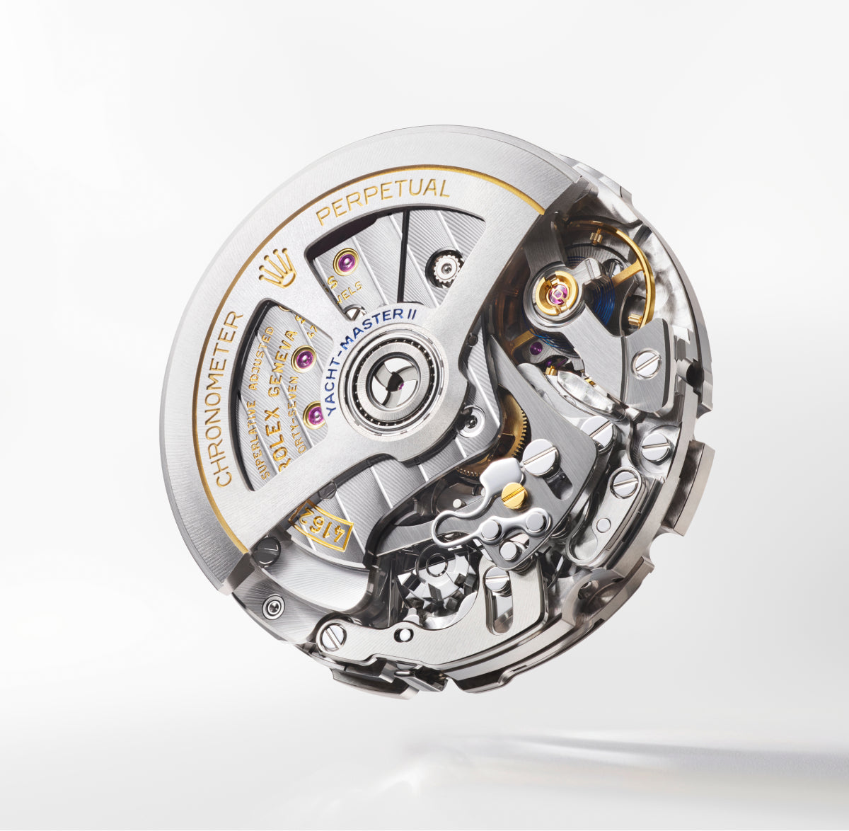 Eine Nahaufnahme eines Rolex Yacht-Master II-Uhrwerks mit sichtbaren Zahnrädern, silbernen und goldenen Komponenten und eingraviertem Text wie Chronometer, Perpetual und Yacht-Master II auf weißem Hintergrund.