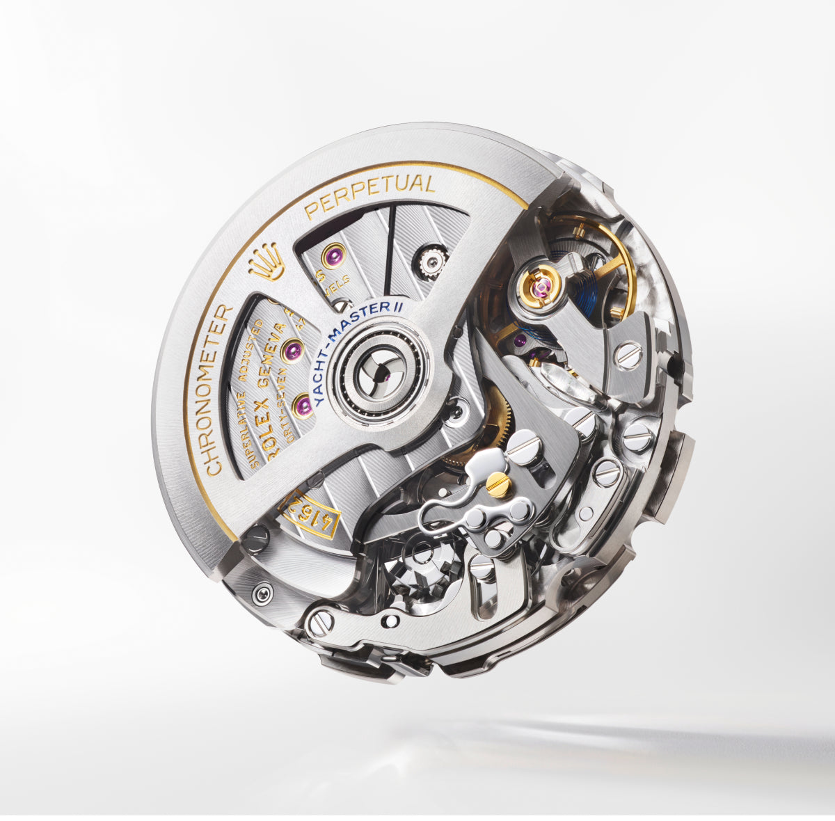 Nahaufnahme eines Rolex Yacht-Master II-Uhrwerks mit komplizierten Zahnrädern, Hebeln und Metallkomponenten mit goldenen Buchstaben und Details auf einer silbernen und metallischen Oberfläche.