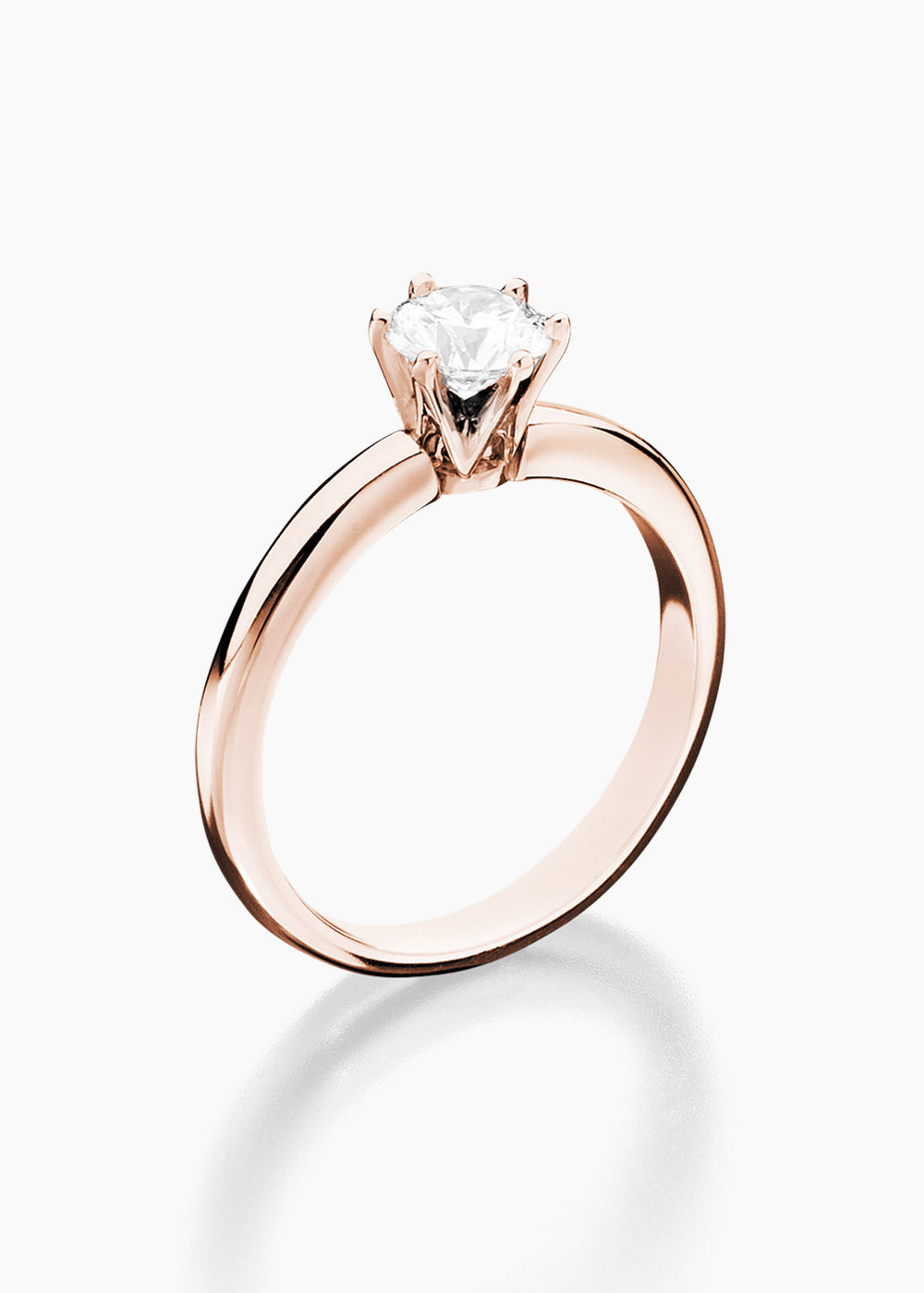 Ein Verlobungsring aus Roségold mit einem einzelnen runden Diamanten im Brillantschliff in einer Sechskantfassung vor weißem Hintergrund.